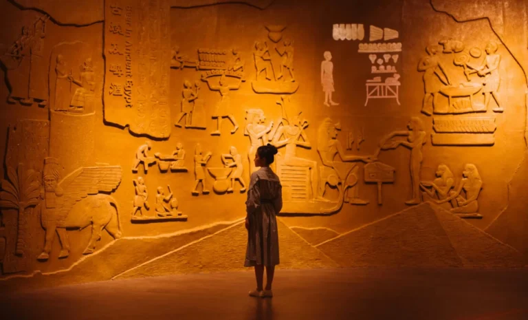 Back view of anonymous female traveler standing near ancient wall with Egyptian engraving