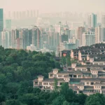 Urban skyline with densely packed skyscrapers and green foreground, depicting urban and natural elements.