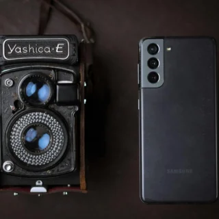 A vintage Yashica camera next to a modern smartphone, showcasing old and new technology.
