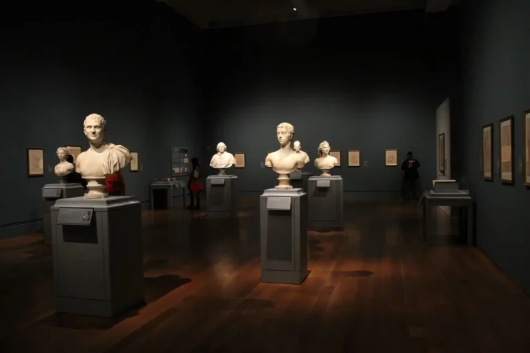 An art gallery with classical sculptures and framed art, showcasing elegant indoor lighting and design.